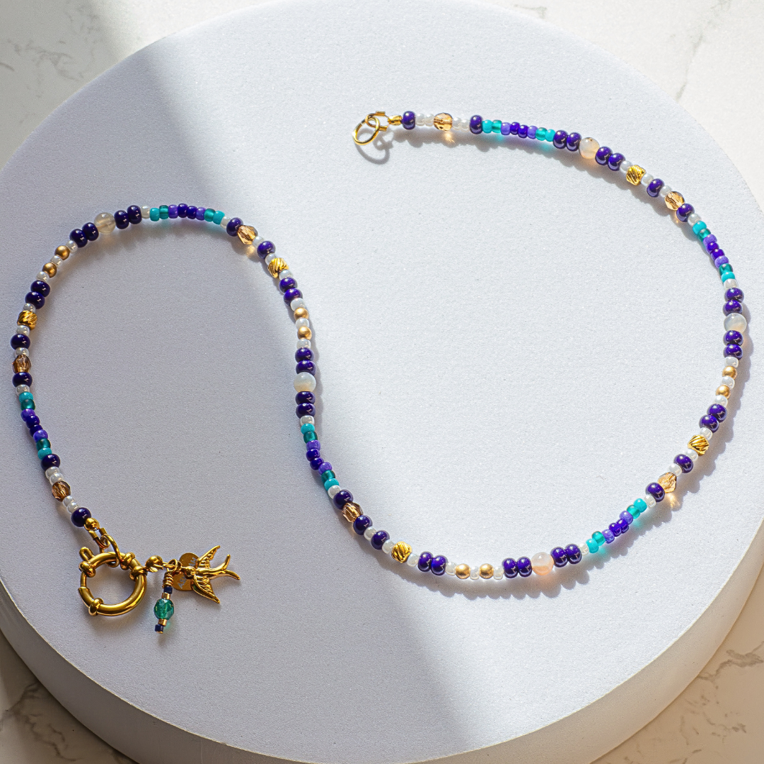 Full length European Roller beaded necklace on white background. Gold tone 19-strand wire with stainless steel ring clasp. 50cm chain.