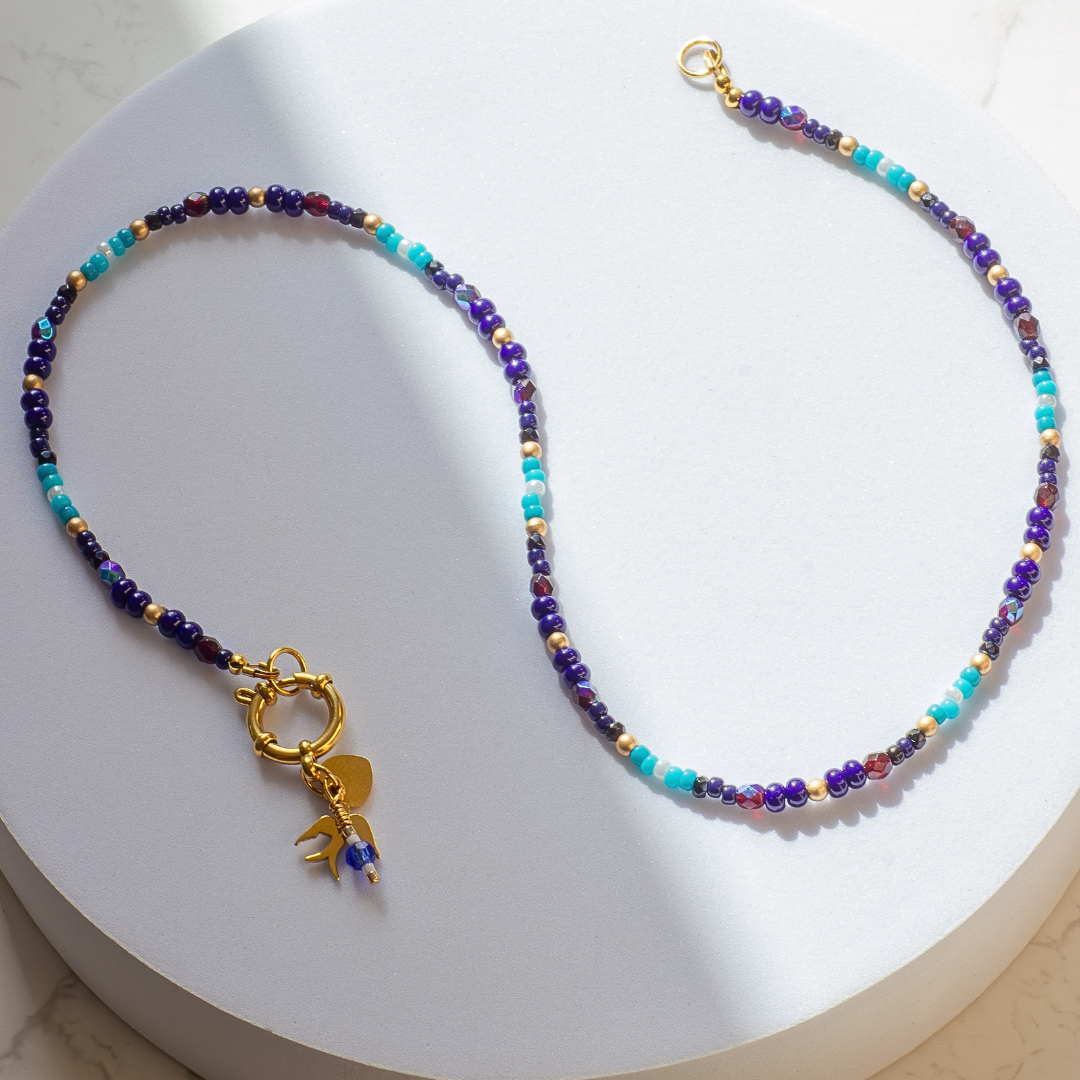 Full length Palestine Sunbird beaded necklace on white background. Gold tone 19-strand wire with stainless steel ring clasp. 50cm chain.