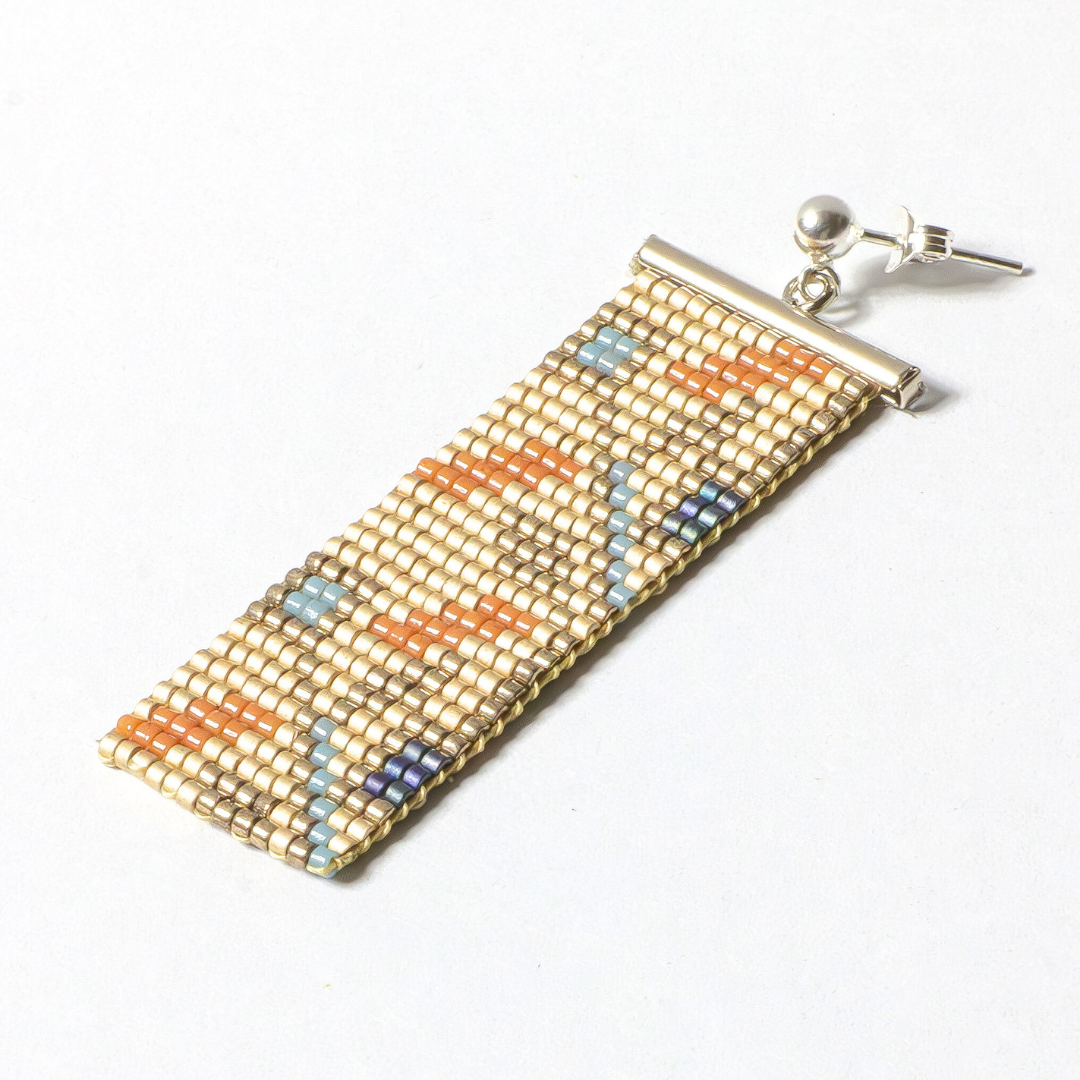 a single handwoven earring on a white background