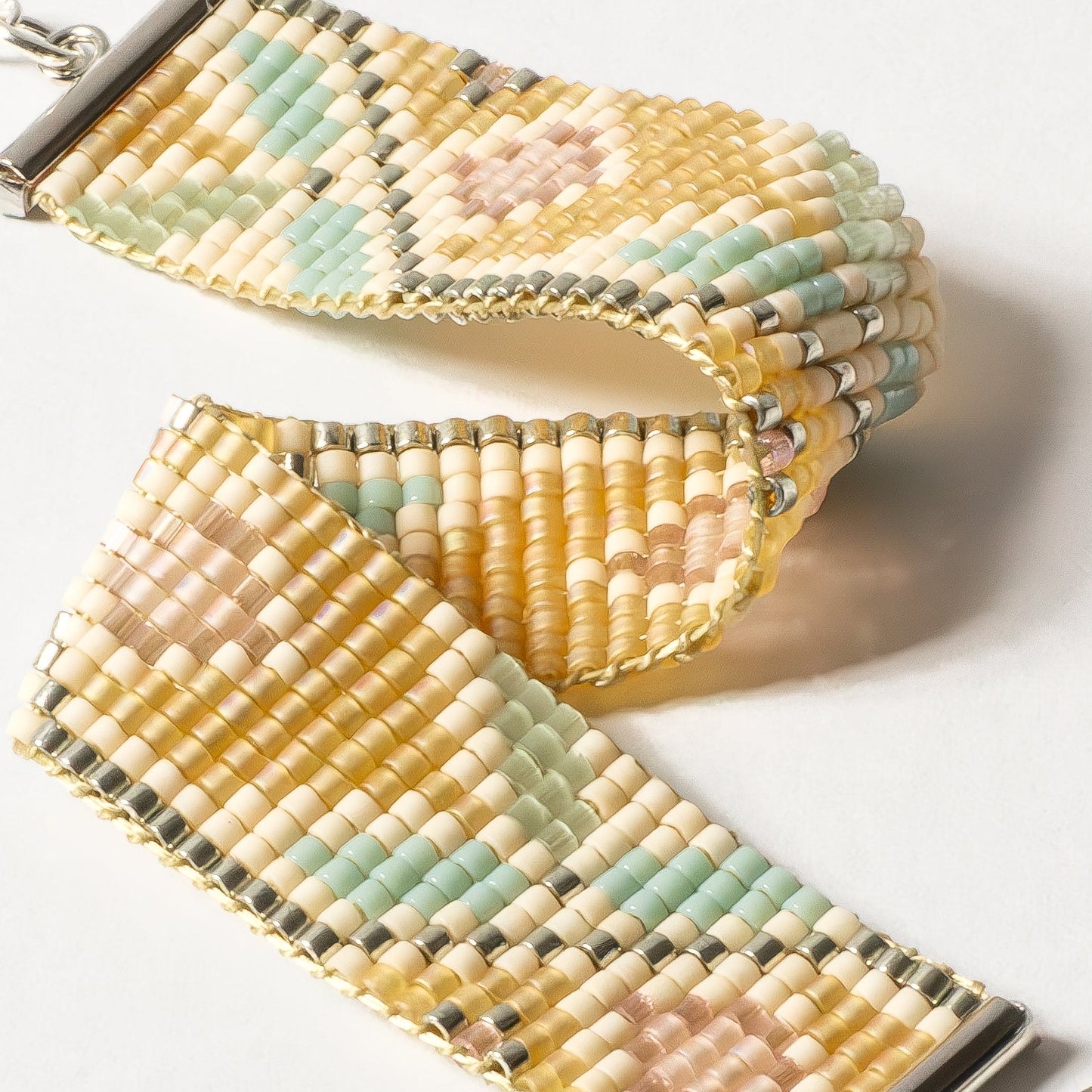Beaded bracelet with a chain and charm on a white background