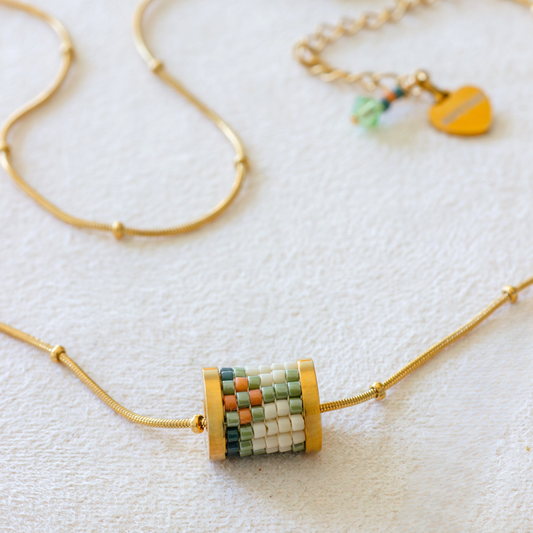 Hand-beaded Tatreez tube necklace in cactus green, cedar brown, evergreen and dark cream on white background. Miyuki glass beads on 304L stainless steel serpentine choker.