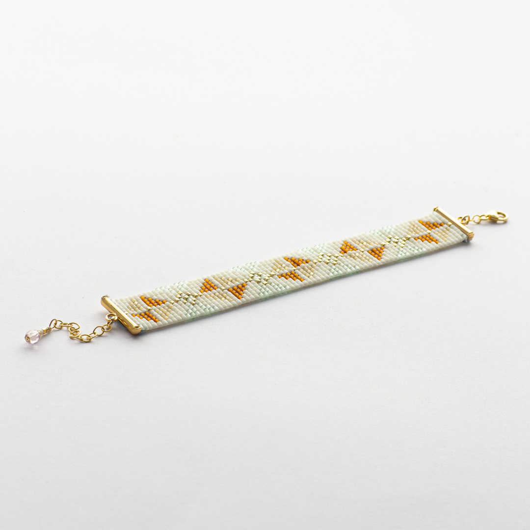 The Chain bracelet showcasing a Tatreez pattern from Yafa in honey opal, cream and mint green and gold