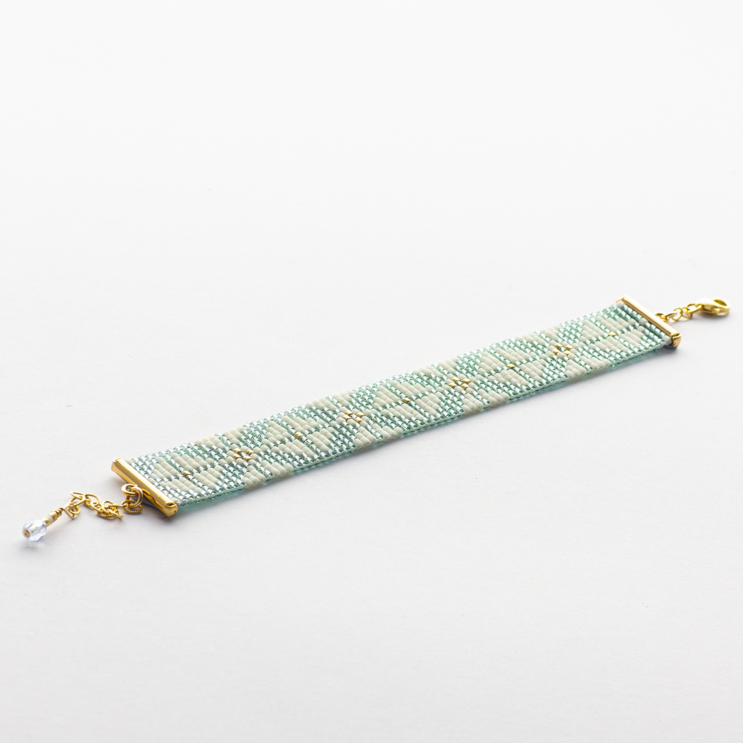 The Chain bracelet showcasing a Tatreez pattern from Yafa in teal, cream, and gold