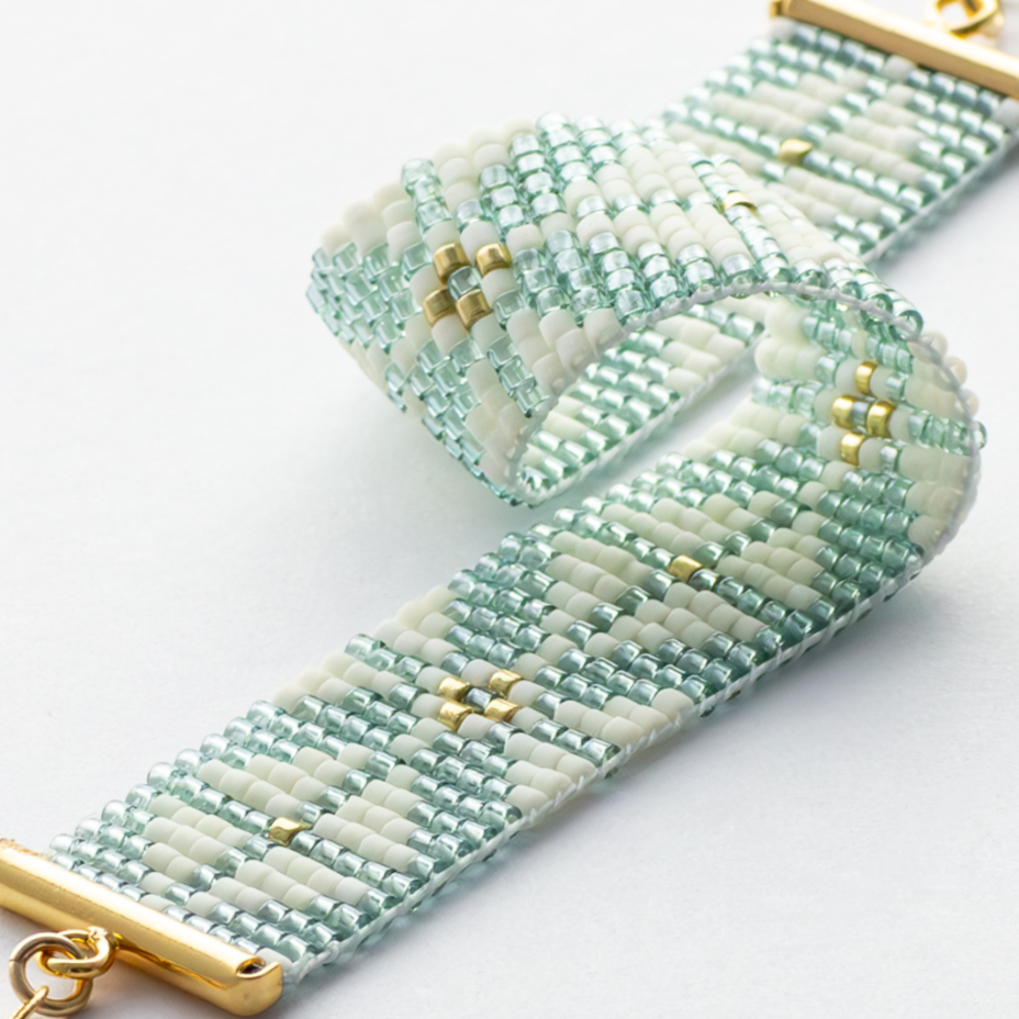 The Chain bracelet showcasing a Tatreez pattern from Yafa in teal, cream, and gold