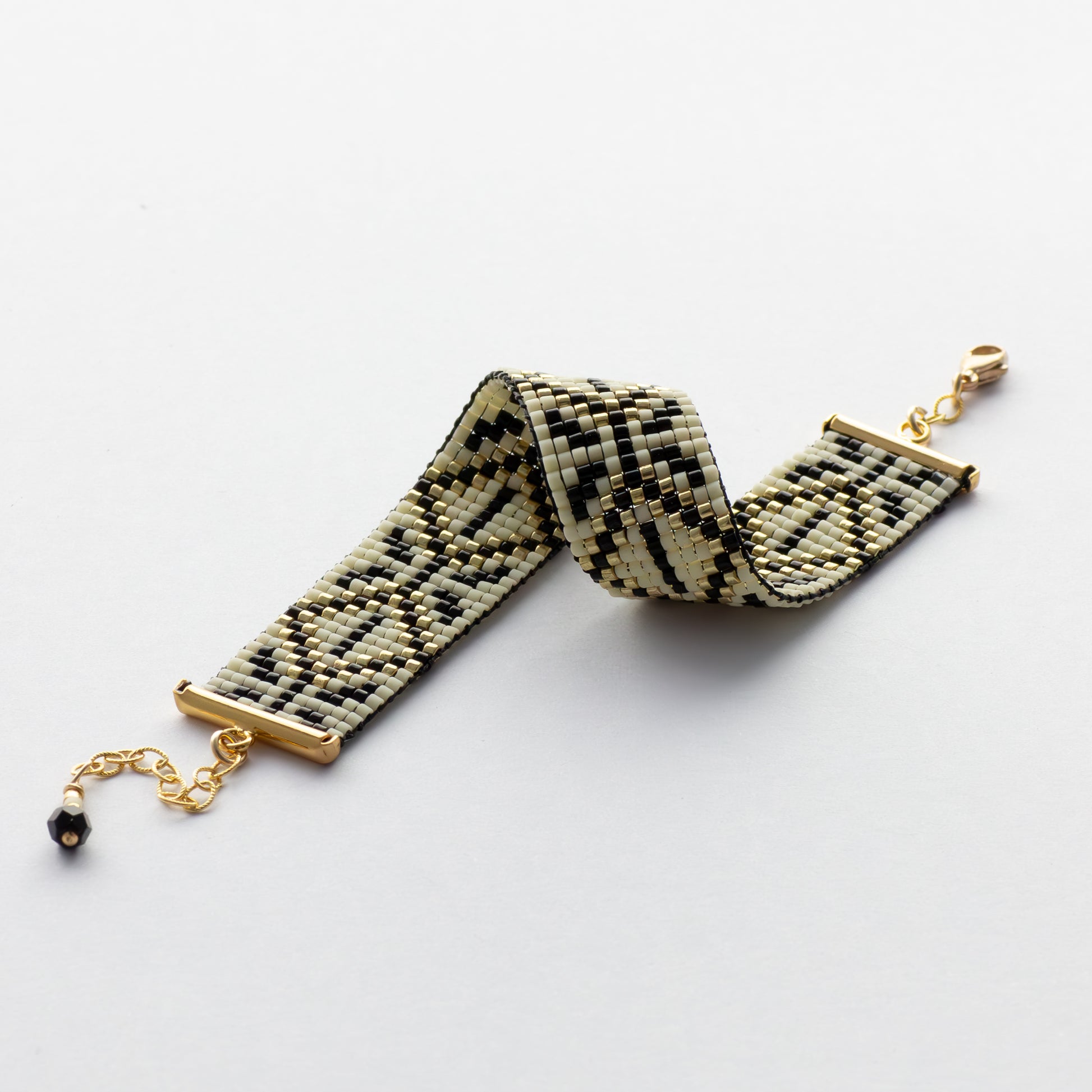 Amulet Bracelet from Al Khalil featuring the Palestinian Tatreez pattern in dark cream, black, and gold accents.