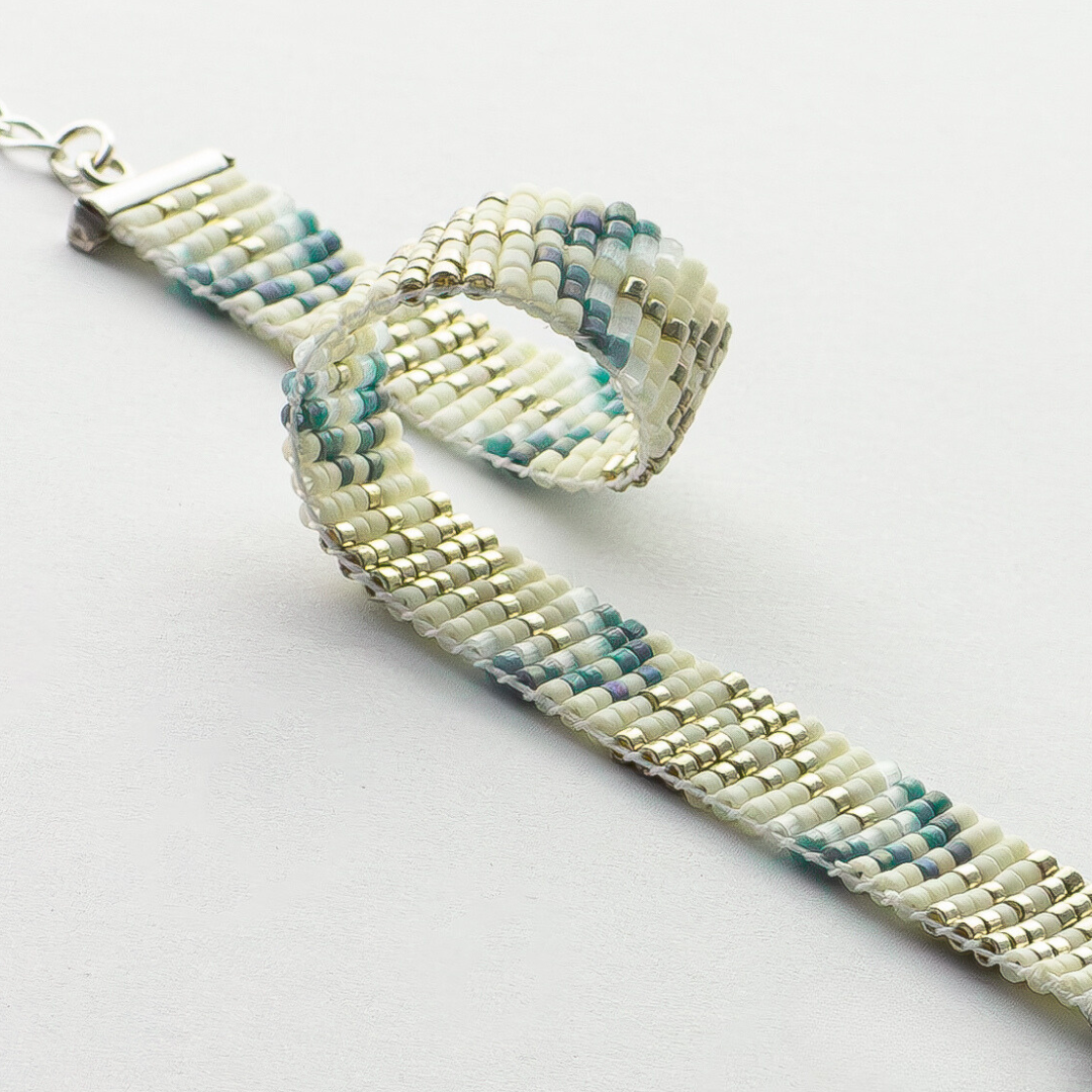 The Trees bracelet showcasing a Tatreez pattern from Esdud in Blue and Cream and Silver