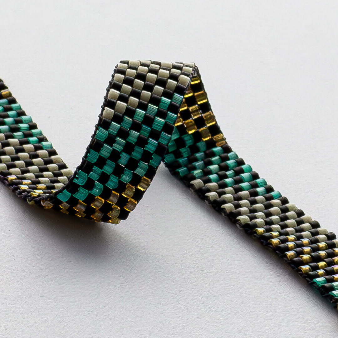 Feathers bracelet showcasing a Tatreez pattern from Al Khalil in matte black, dark cream, turquoise green, and amber accents