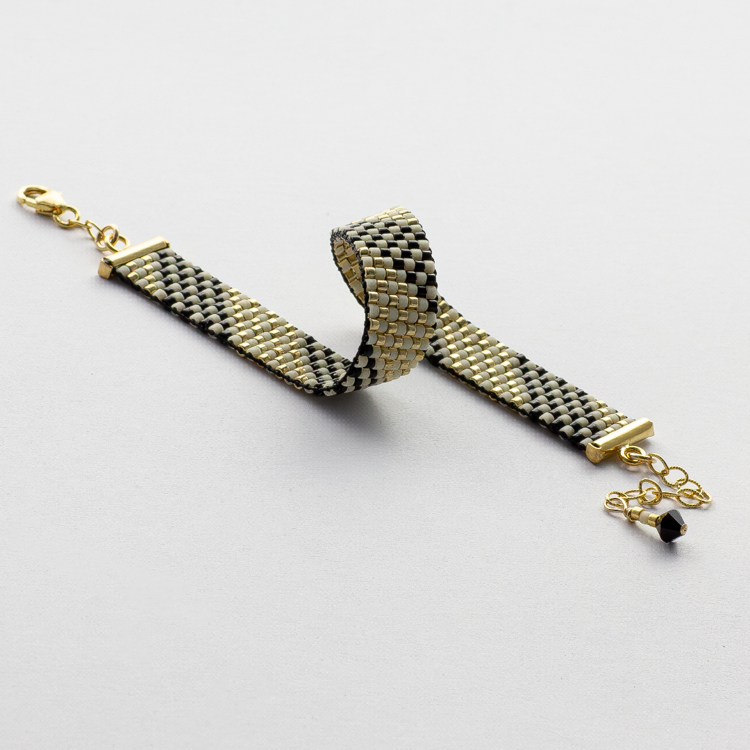 Feathers bracelet showcasing a Tatreez pattern from Al Khalil in dark cream, black, and gold accents