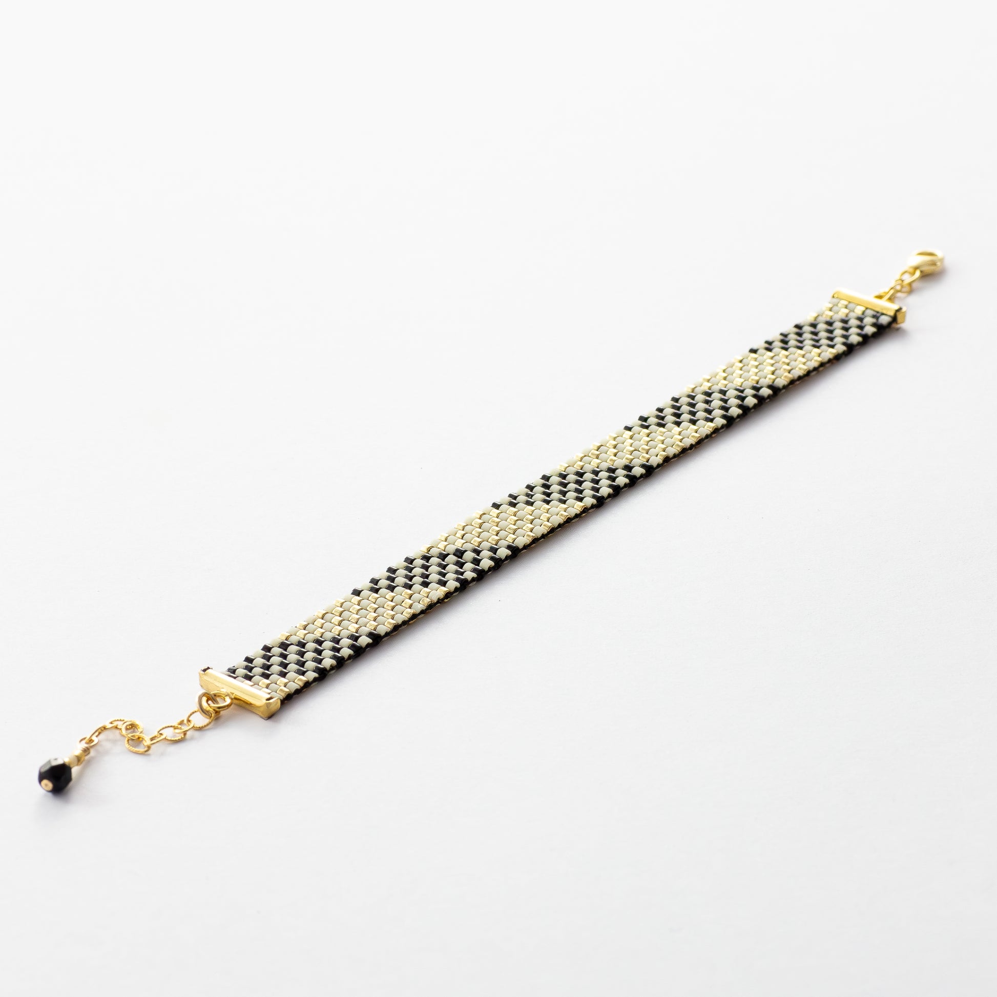 Feathers bracelet showcasing a Tatreez pattern from Al Khalil in dark cream, black, and gold accents