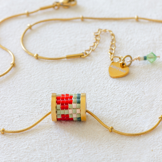 Hand-beaded Tatreez tube necklace in fennel green, evergreen, orange red and light salmon on white background. Miyuki glass beads on 304L stainless steel serpentine choker.