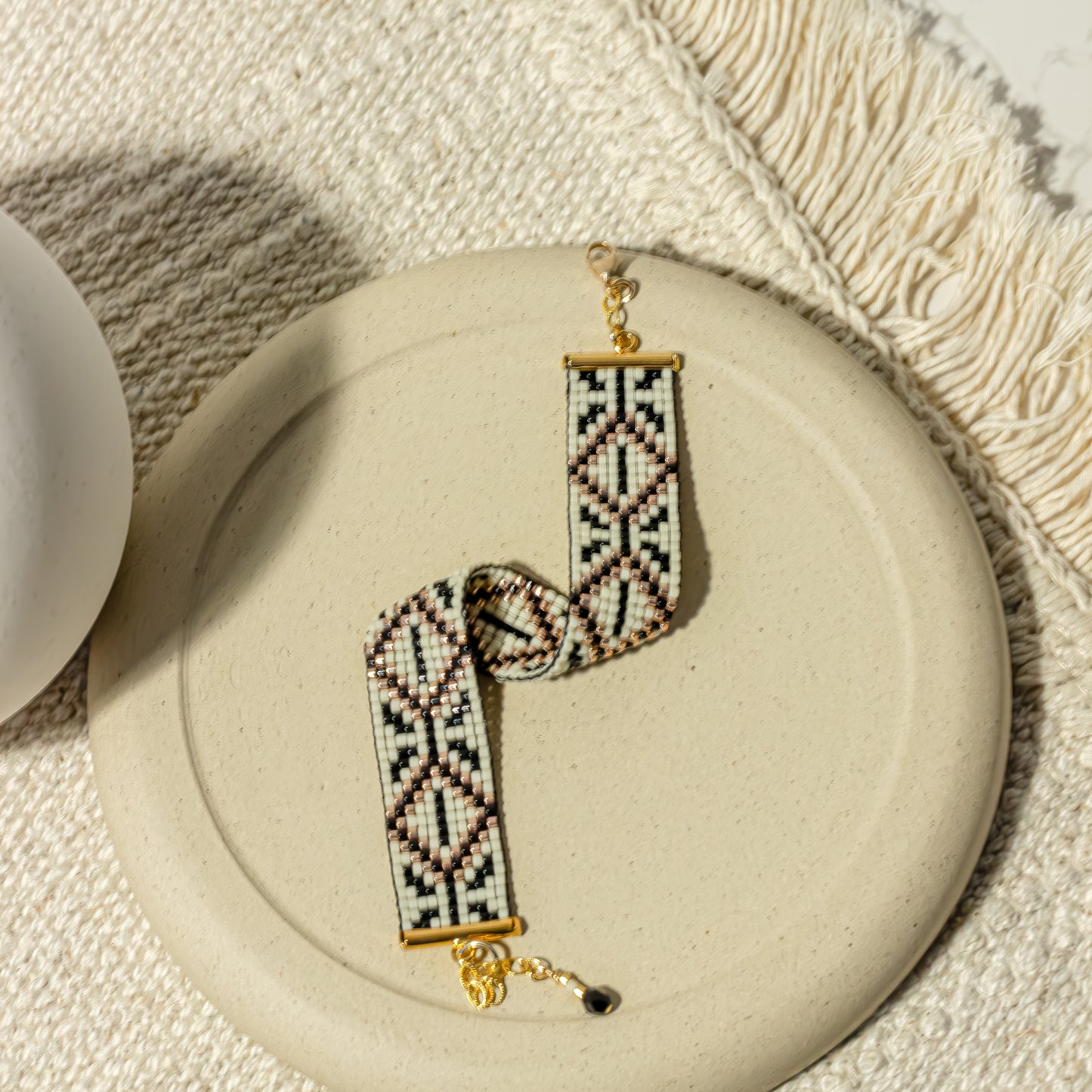 Amulet Bracelet from Al Khalil featuring the Palestinian Tatreez pattern in dark cream, black, and gold accents.