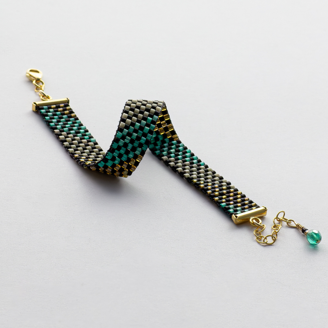 Feathers bracelet showcasing a Tatreez pattern from Al Khalil in matte black, dark cream, turquoise green, and amber accents