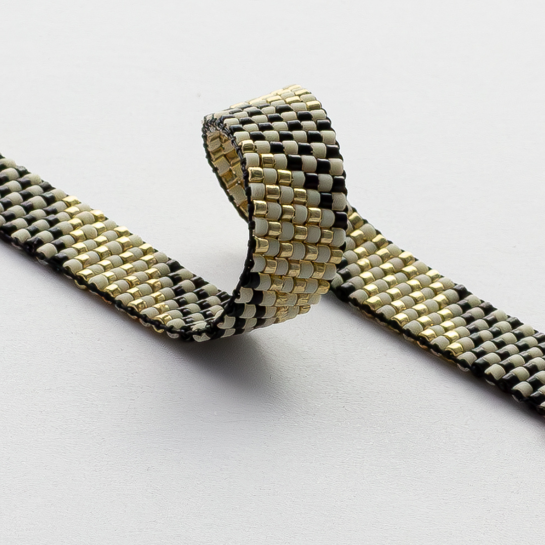 Feathers bracelet showcasing a Tatreez pattern from Al Khalil in dark cream, black, and gold accents