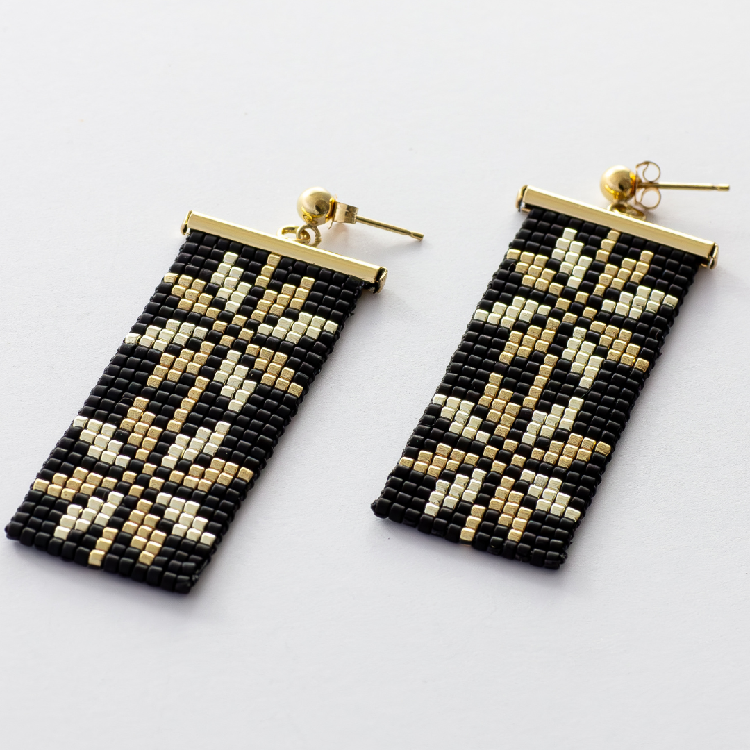 Moon of Bethlehem earrings featuring the Palestinian Tatreez pattern in gold and silver against a matte black background