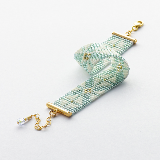 The Chain bracelet showcasing a Tatreez pattern from Yafa in teal, cream, and gold