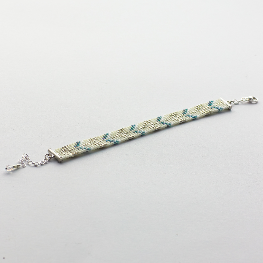 The Trees bracelet showcasing a Tatreez pattern from Esdud in Blue and Cream and Silver