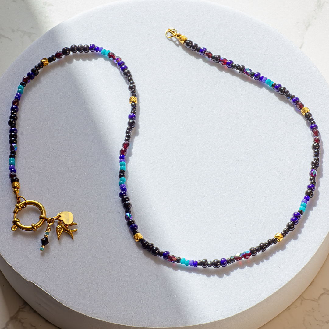 Full length Palestine Sunbird beaded necklace on white background. Gold tone 19-strand wire with stainless steel ring clasp. 50cm chain.
