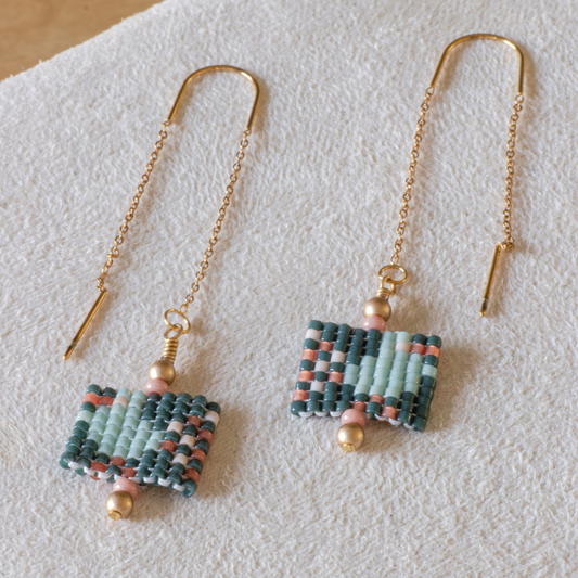 Hand-beaded Tatreez threader earrings in evergreen, pale turquoise, rose and papaya orange on white background. Asafir bird motif in Miyuki Delica beads on 304L stainless steel.