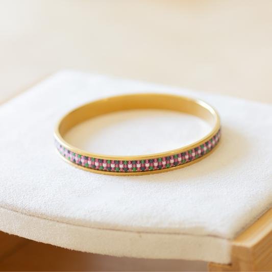 Hand-beaded Tatreez bangle in bubblegum pink, green, evergreen and cream on white background. Three-row Miyuki glass bead pattern on 304 stainless steel.