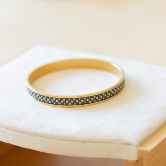 Hand-beaded Tatreez bangle in evergreen, pale turquoise, rose and papaya orange on white background. Three-row Miyuki glass bead pattern on 304 stainless steel.
