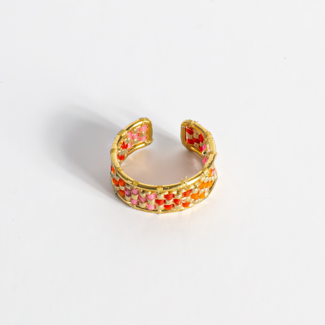 Hand-beaded Tatreez ring in orange-red, orange, bubblegum pink, pink mist and gold on white background. Front view.Gold Filled setting.