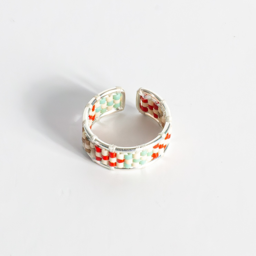Hand-beaded Tatreez ring in true red, silver, antique beige, sea foam and champagne on white background. Front view. Sterling silver setting.