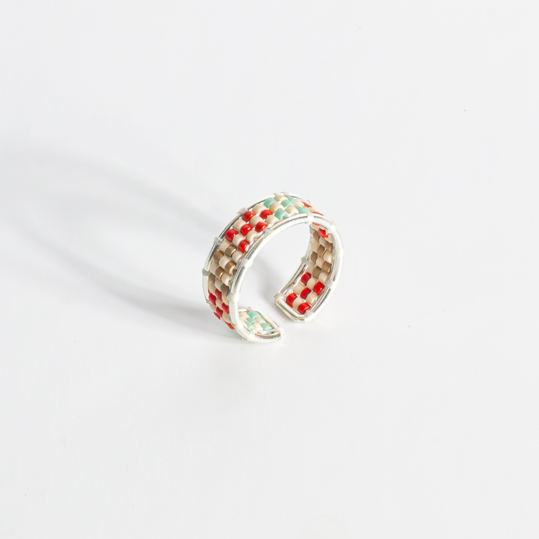 Hand-beaded Tatreez ring in true red, silver, antique beige, sea foam and champagne on white background. Front view. Sterling silver setting.