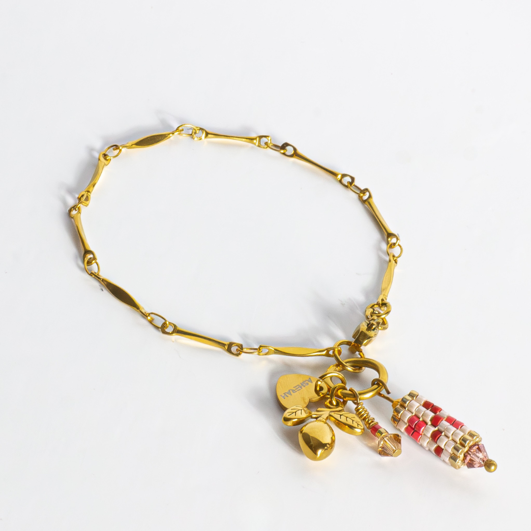 Tatreez charm bracelet in brick red, pink champagne, gold and cranberry on white background. Features cylindrical Tatreez charm and olive charm on fancy gold stainless steel chain.