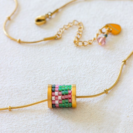 Hand-beaded Tatreez tube necklace in bubblegum pink, green, evergreen and cream on white background. Miyuki glass beads on 304L stainless steel serpentine choker.