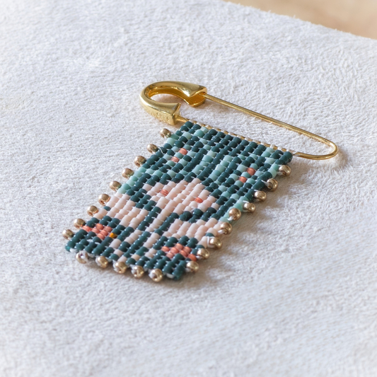 Hand-beaded Tatreez brooch in evergreen, pale turquoise, rose and papaya orange. Tum Al Samakeh Snapdragon motif on gold-finish 925 sterling silver.