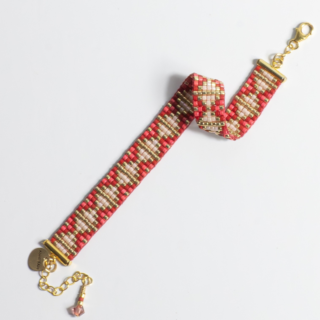 Hand-beaded Tatreez woven bracelet in brick red, pink champagne, gold and cranberry on white background. Full view. Available with adjustable stainless steel clasp or gold-filled lobster clasp.