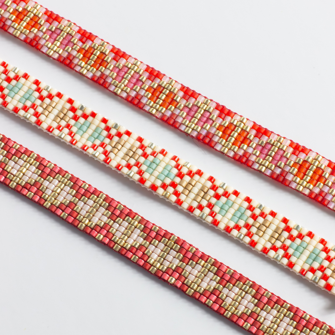 Three hand-beaded Tatreez woven bracelets on white background. Left: brick red. Middle: orange red . Right: orange-red.